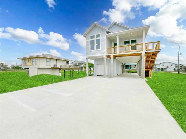 beach home featuring a porch, a garage, a front lawn, and a carport