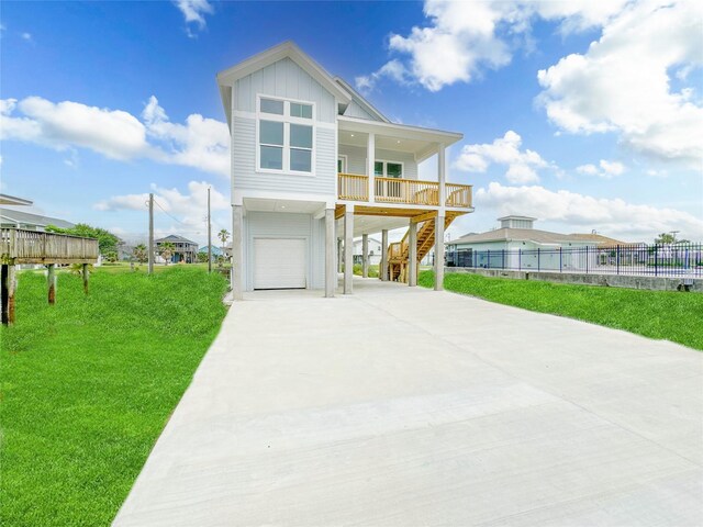 view of front facade featuring covered porch, a carport, a garage, and a front lawn