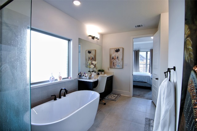 bathroom with tile flooring, a bath to relax in, vanity, and a wealth of natural light