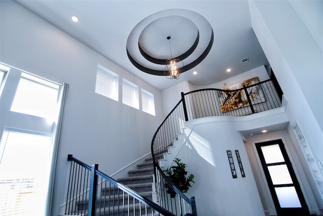 stairs with plenty of natural light, a raised ceiling, and a high ceiling