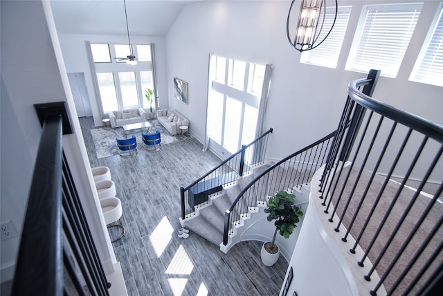 stairs featuring ceiling fan with notable chandelier, hardwood / wood-style floors, and a towering ceiling