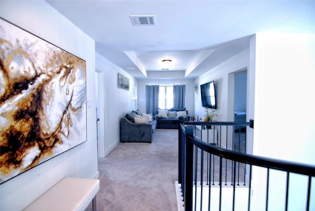 hall featuring light colored carpet and a tray ceiling