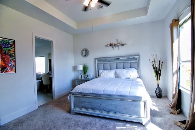 carpeted bedroom with connected bathroom, ceiling fan, and a raised ceiling