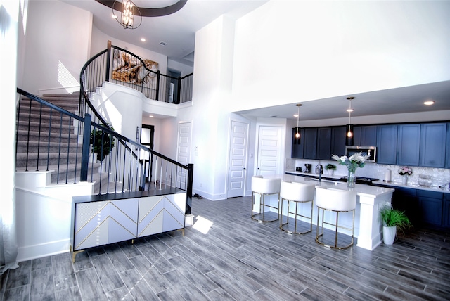 kitchen with pendant lighting, tasteful backsplash, a high ceiling, a kitchen breakfast bar, and a kitchen island with sink