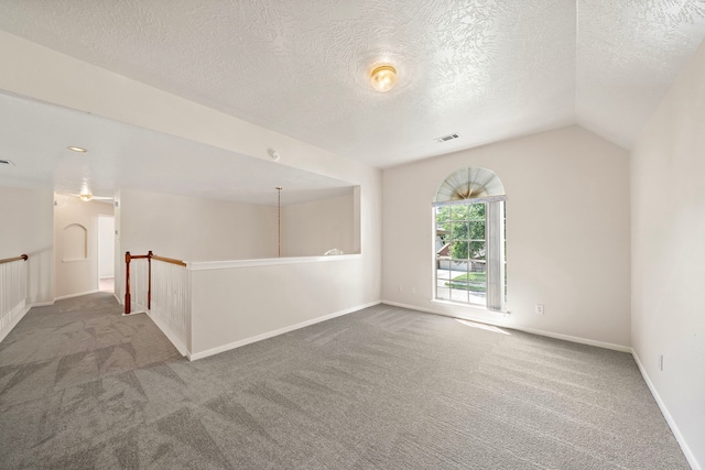 spare room featuring carpet flooring, lofted ceiling, and a textured ceiling