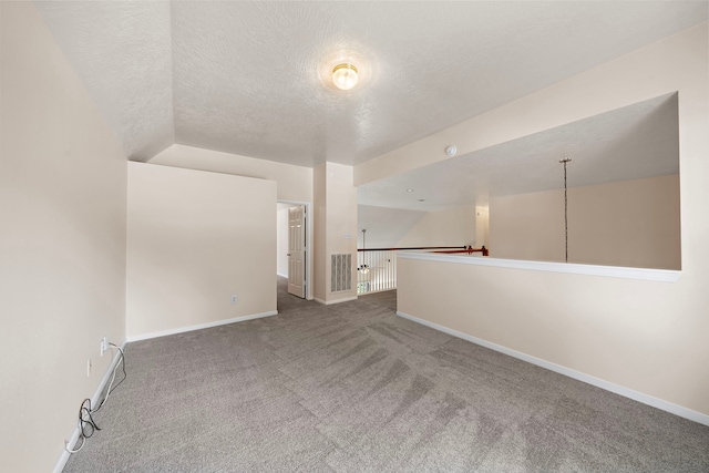 spare room with lofted ceiling, carpet, and a textured ceiling