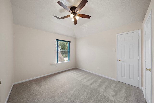 carpeted spare room featuring a textured ceiling, ceiling fan, and lofted ceiling