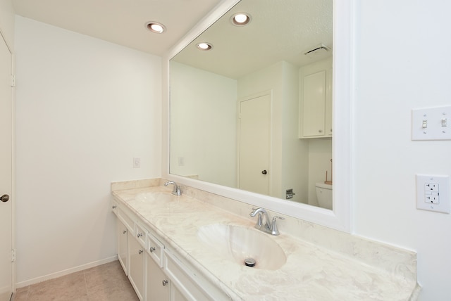 bathroom featuring tile flooring, toilet, and dual vanity