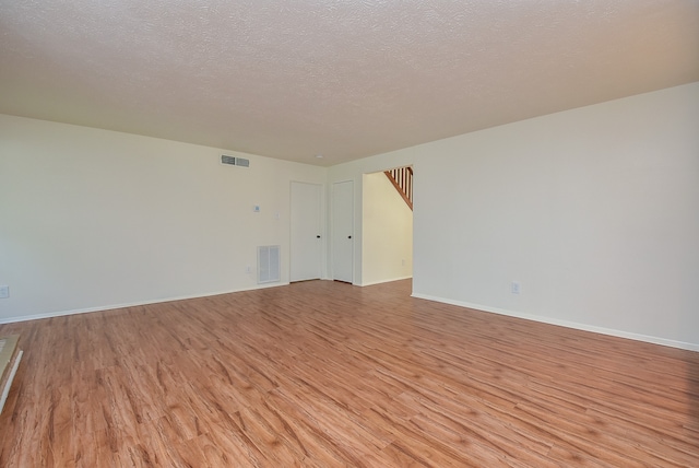 empty room with a textured ceiling and light hardwood / wood-style floors