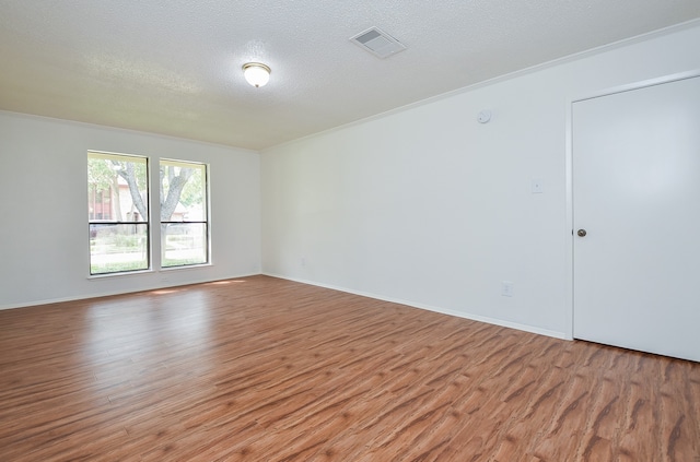 spare room with ornamental molding, a textured ceiling, and hardwood / wood-style floors