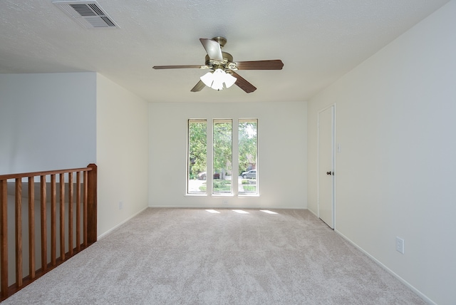 carpeted empty room featuring ceiling fan and a textured ceiling