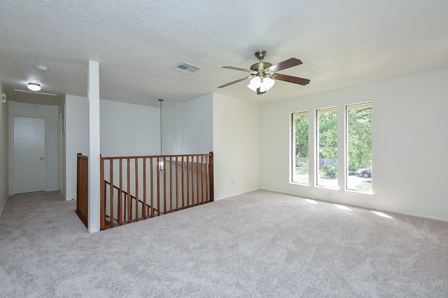 carpeted empty room with ceiling fan and a textured ceiling