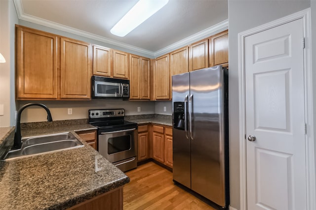 kitchen with appliances with stainless steel finishes, light hardwood / wood-style floors, dark stone counters, sink, and ornamental molding