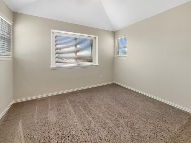 spare room with vaulted ceiling and dark colored carpet