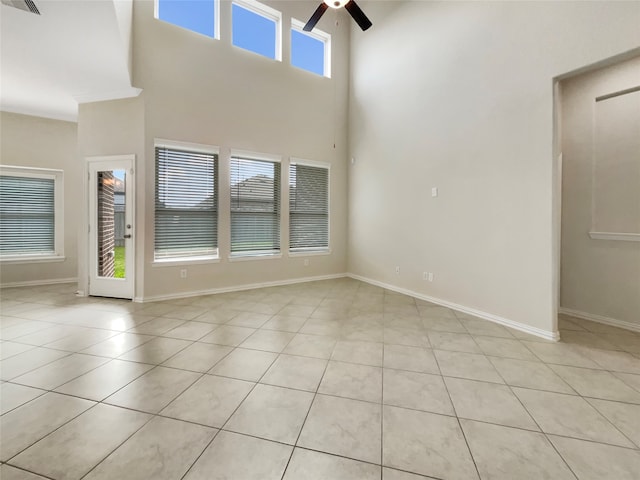 spare room with ceiling fan, light tile floors, a high ceiling, and plenty of natural light