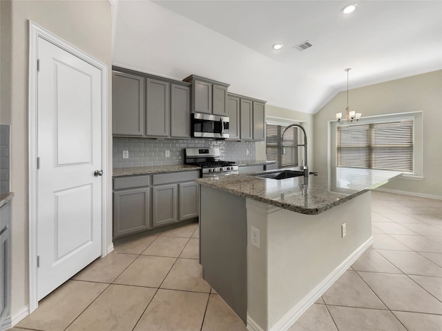 kitchen with appliances with stainless steel finishes, sink, tasteful backsplash, vaulted ceiling, and a kitchen island with sink