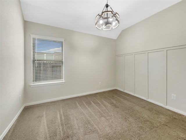 carpeted empty room featuring vaulted ceiling and a notable chandelier