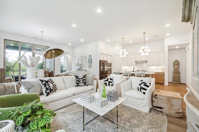 living room with a wealth of natural light, light hardwood / wood-style floors, and a chandelier