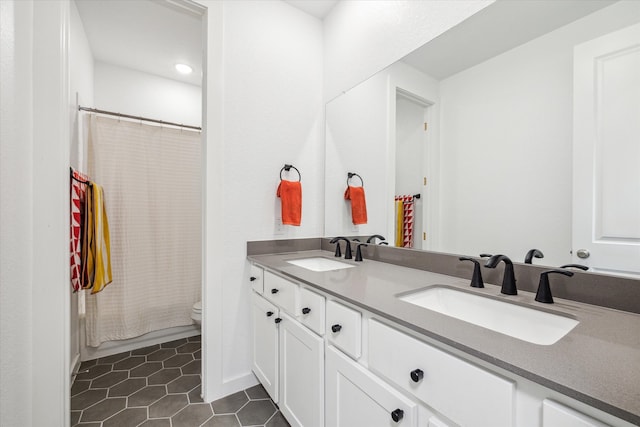 bathroom with toilet, tile floors, vanity with extensive cabinet space, and double sink