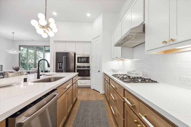 kitchen featuring backsplash, wall chimney range hood, stainless steel appliances, sink, and light hardwood / wood-style floors