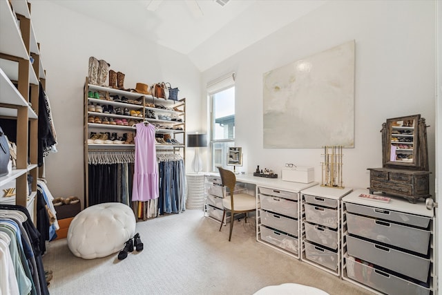 walk in closet with light colored carpet and vaulted ceiling