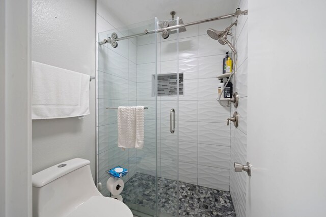 bathroom with a shower with door and toilet