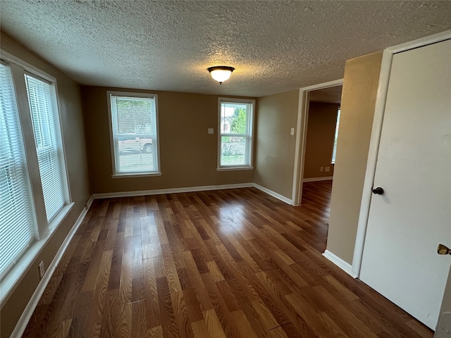 spare room with dark hardwood / wood-style floors and a textured ceiling