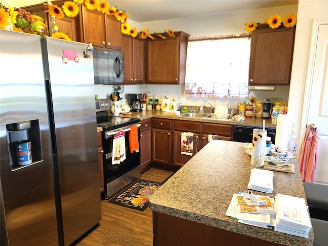 kitchen featuring dark wood-type flooring, black appliances, and sink