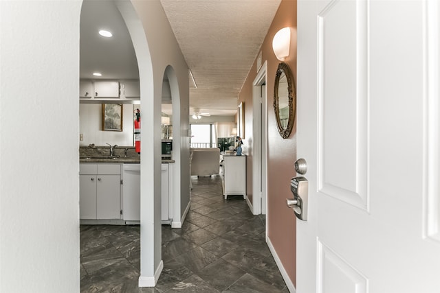 hall with sink, tile flooring, and a textured ceiling