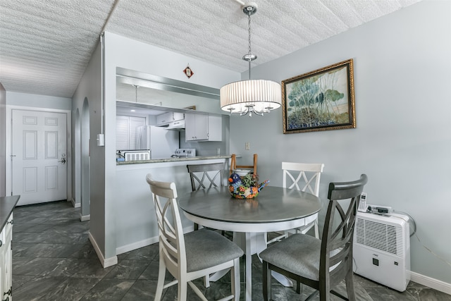 dining space with an inviting chandelier, dark tile floors, and a textured ceiling