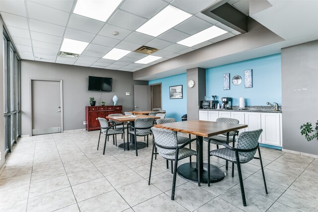 tiled dining room featuring a drop ceiling