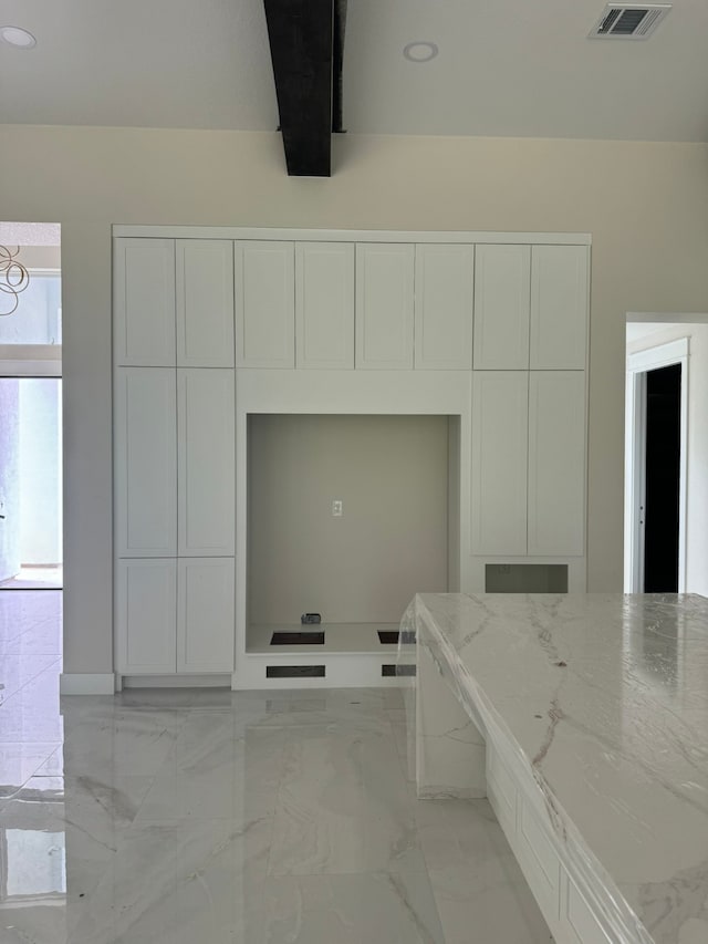 kitchen featuring light stone counters and white cabinets