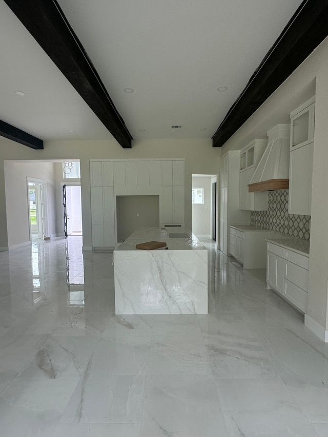 kitchen with beamed ceiling, white cabinets, and tasteful backsplash