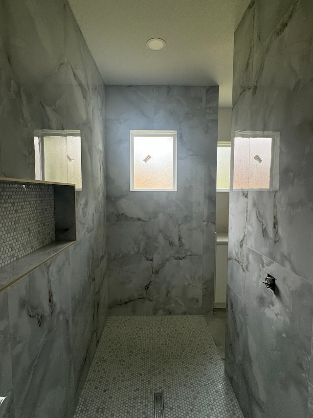 bathroom with tiled shower and tile patterned floors