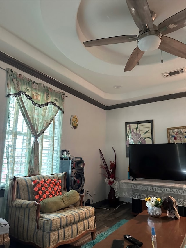 living room featuring hardwood / wood-style floors, ceiling fan, and a raised ceiling