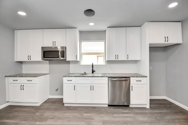 kitchen with sink, appliances with stainless steel finishes, light wood-type flooring, and white cabinets