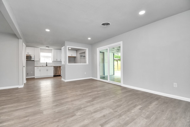 unfurnished living room featuring sink and wood-type flooring