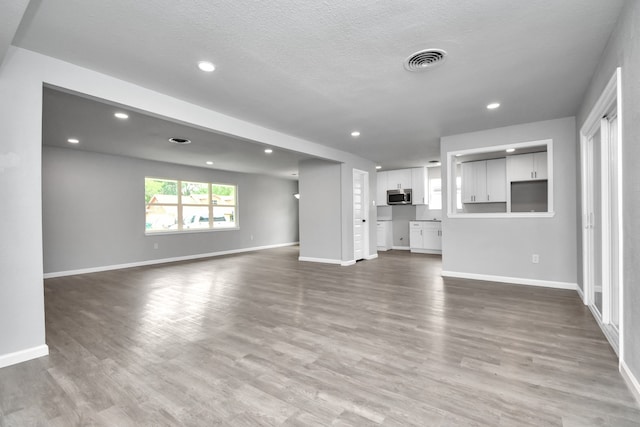 unfurnished living room featuring a textured ceiling and wood-type flooring