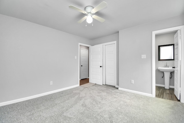 unfurnished bedroom featuring a closet, ceiling fan, sink, light hardwood / wood-style flooring, and ensuite bathroom