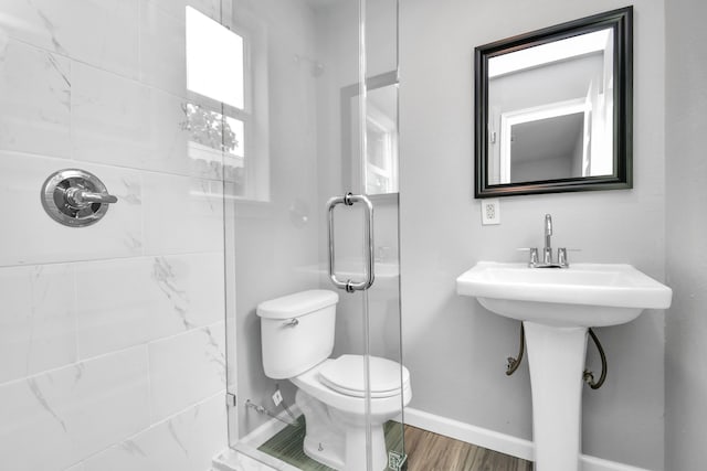 bathroom featuring toilet, wood-type flooring, and an enclosed shower