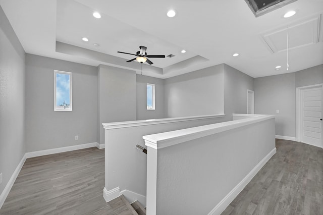 hallway with a raised ceiling and wood-type flooring