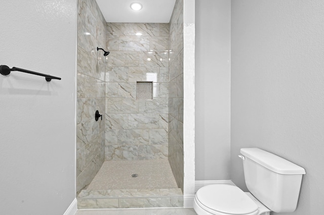 bathroom with tiled shower and toilet