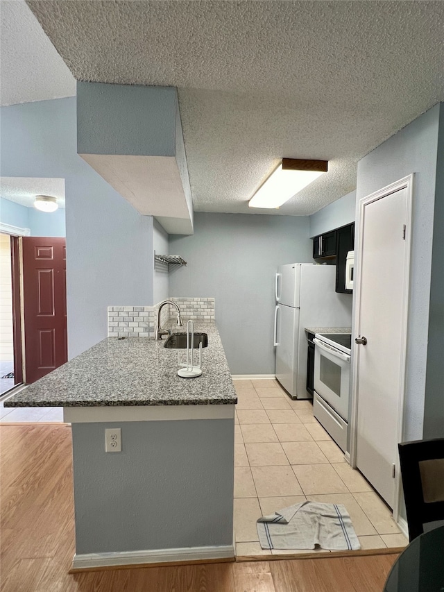 kitchen featuring kitchen peninsula, stone countertops, light tile floors, sink, and stainless steel electric range oven