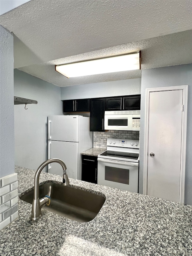 kitchen featuring a textured ceiling, sink, white appliances, backsplash, and stone counters