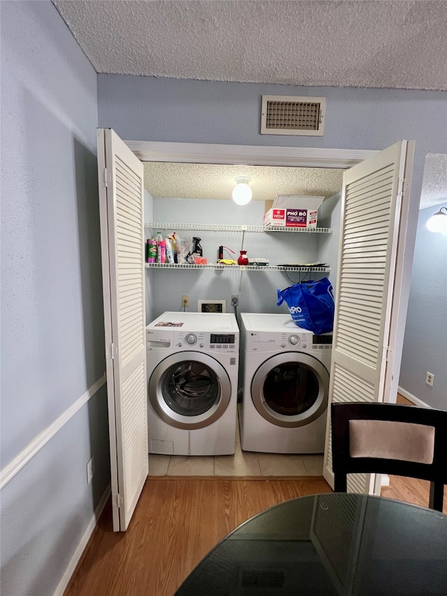 laundry room with hardwood / wood-style flooring, washer hookup, a textured ceiling, and washer and dryer