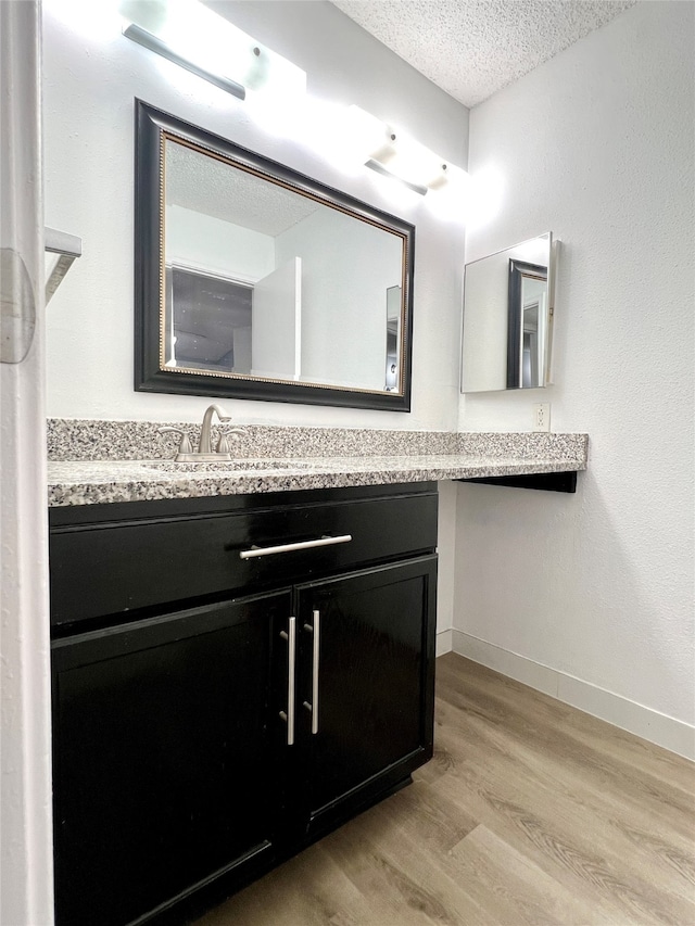 bathroom with a textured ceiling, vanity, and hardwood / wood-style flooring