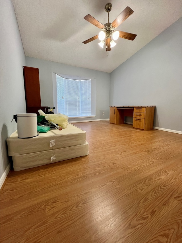 unfurnished bedroom with vaulted ceiling, a textured ceiling, ceiling fan, and hardwood / wood-style floors