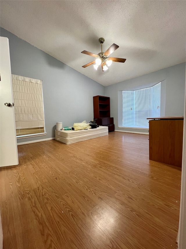 unfurnished room with lofted ceiling, ceiling fan, hardwood / wood-style flooring, and a textured ceiling