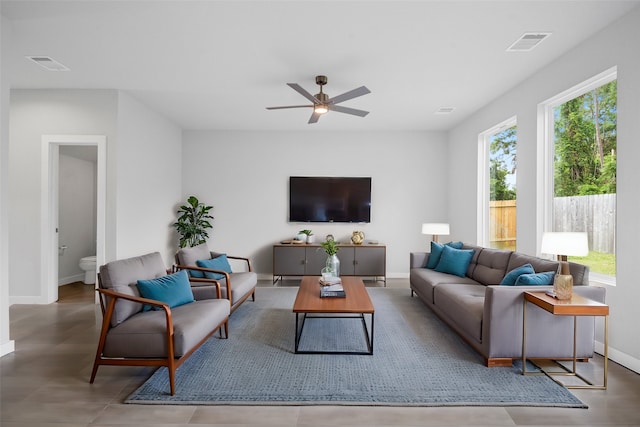 living room featuring a ceiling fan, visible vents, and baseboards