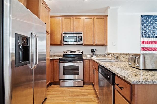 kitchen featuring sink, light hardwood / wood-style floors, crown molding, stainless steel appliances, and light stone countertops